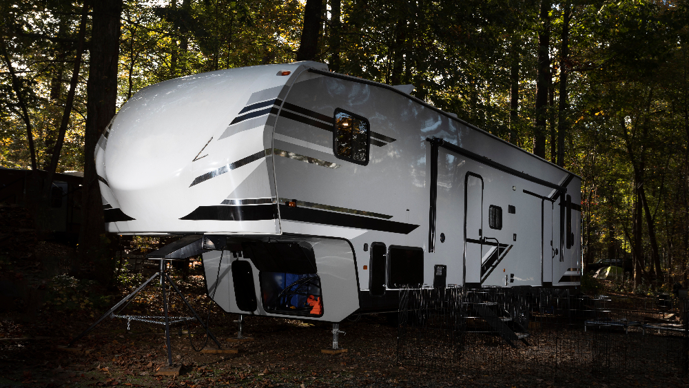A fifth wheel RV parked in a forest.